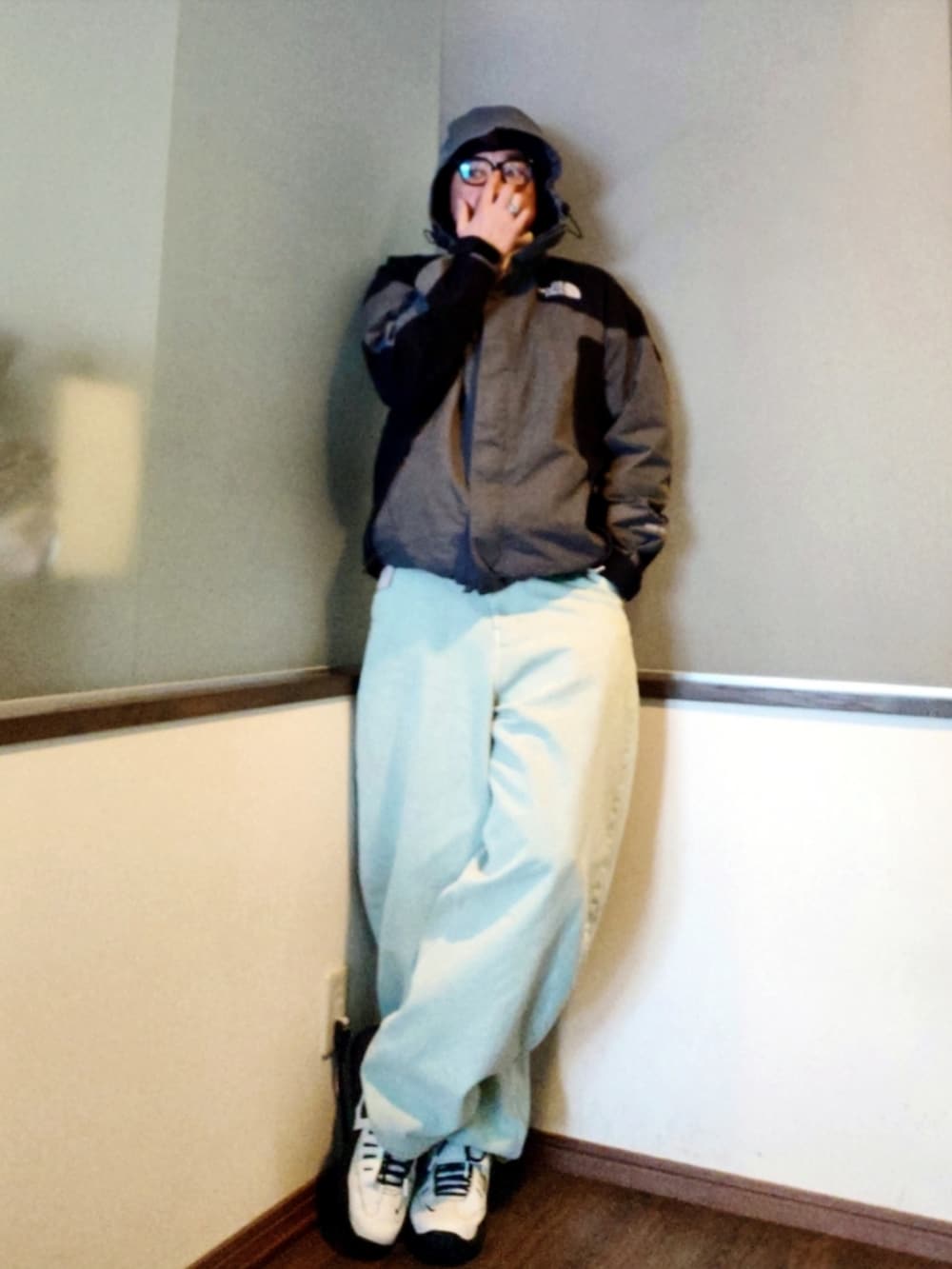 グレー系のマウンテンパーカー、グリーン系のニット/セーター、ブルー系のデニムパンツを着用したメンズの春コーディネートの4枚目の写真