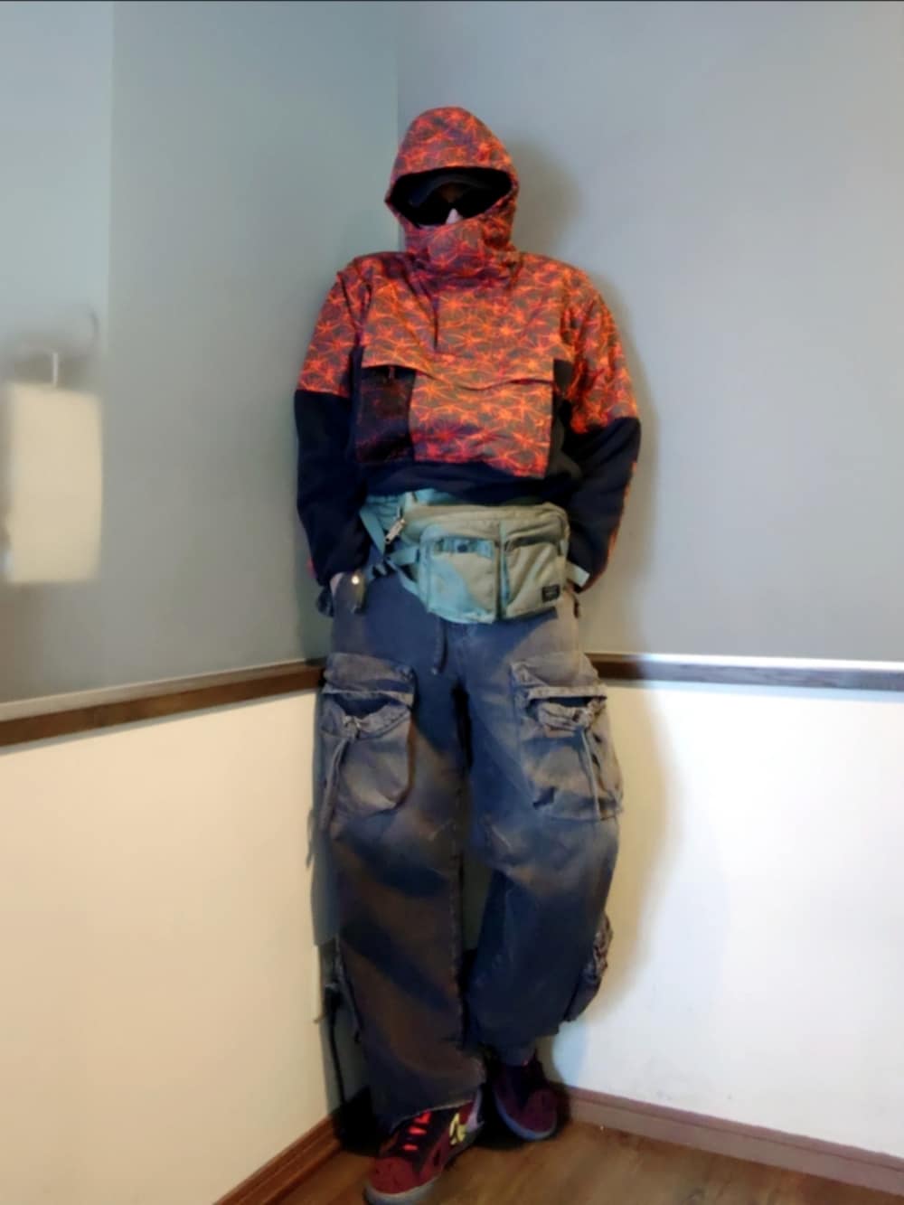 レッド系のブルゾン、ブラック系のカーゴパンツ、レッド系のスニーカーを着用したメンズの春コーディネートの3枚目の写真