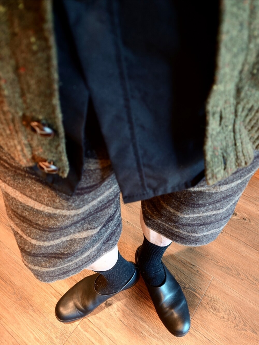 グリーン系のカーディガン/ボレロ、ブラウン系のその他パンツ、ブラック系のスリッポンを着用したメンズの秋コーディネートの2枚目の写真