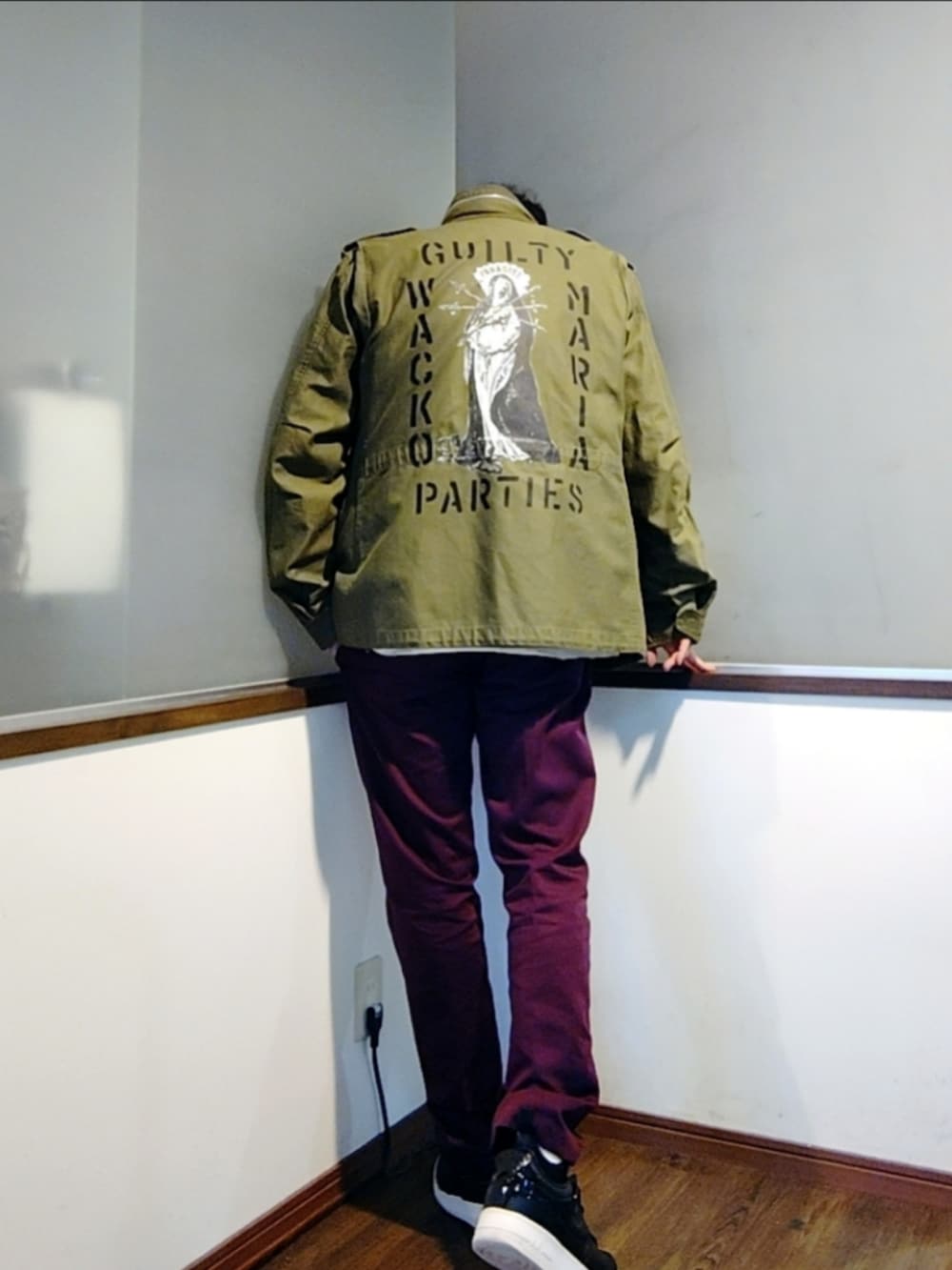 レッド系のカバーオール、レッド系のチノパンツ、ブラック系のスニーカーを着用したメンズの秋コーディネートの4枚目の写真
