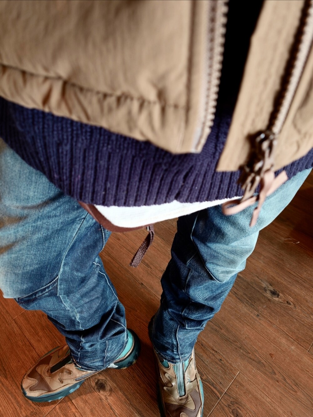 ベージュ系のダウンジャケット/コート、ブルー系のニット/セーター、ブルー系のデニムパンツを着用したメンズの冬コーディネートの5枚目の写真