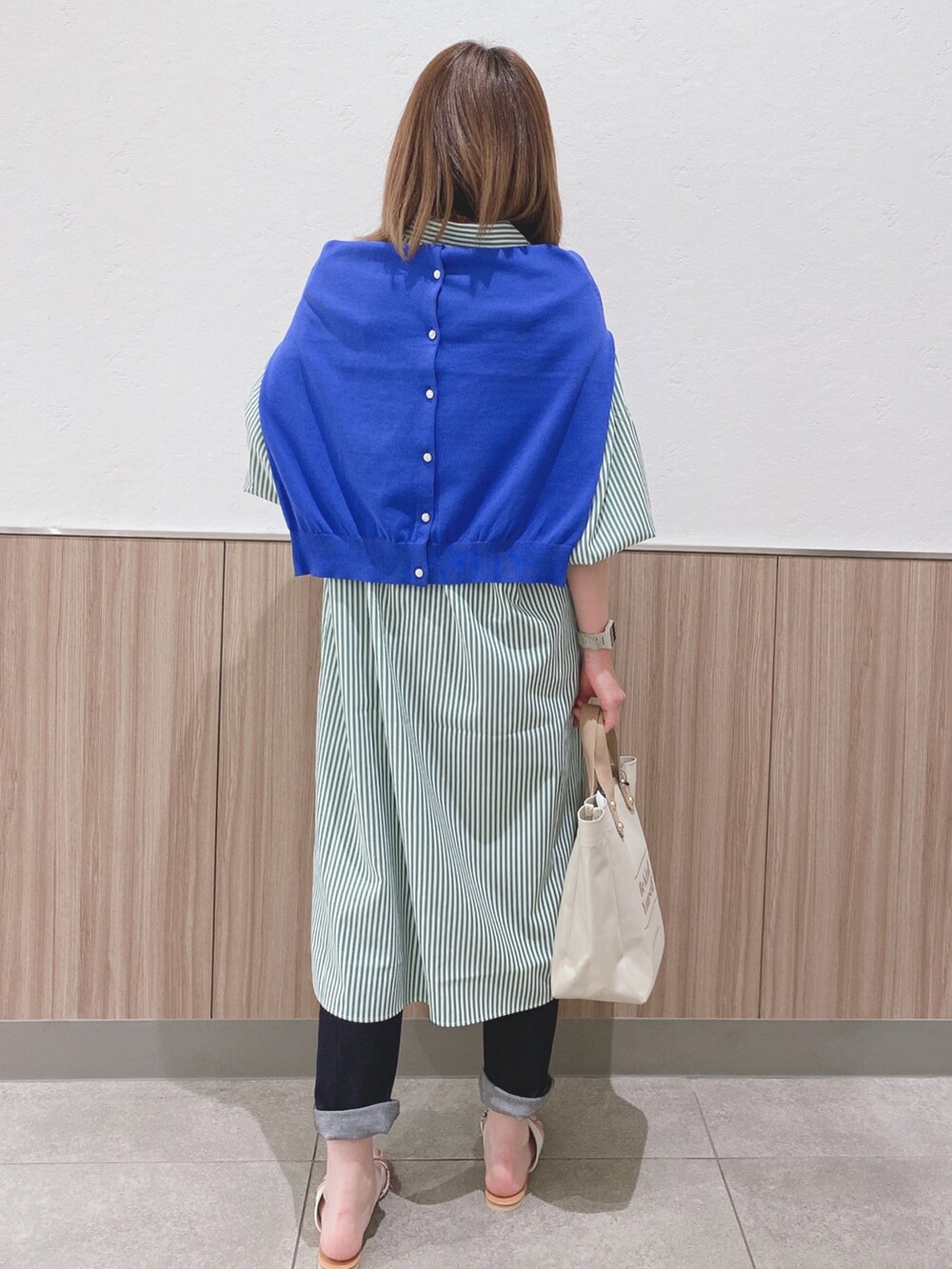 グリーン系のワンピース、ブルー系のカーディガン/ボレロ、ベージュ系のトートバッグを着用したレディースの春コーディネートの3枚目の写真