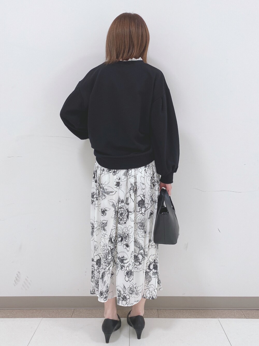 ブラック系のスウェット、ホワイト系のスカート、ブラック系のパンプスを着用したレディースの春コーディネートの3枚目の写真