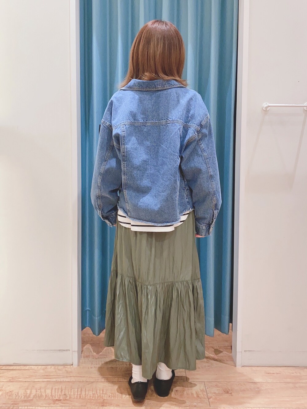 ブルー系のデニムジャケット、ブラック系のTシャツ/カットソー、グリーン系のスカートを着用したレディースの春コーディネートの3枚目の写真