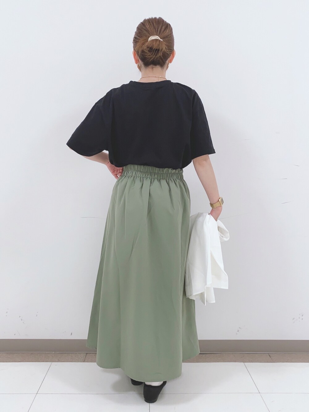 ブラック系のTシャツ/カットソー、グリーン系のスカート、ホワイト系のシャツ/ブラウスを着用したレディースの春コーディネートの3枚目の写真