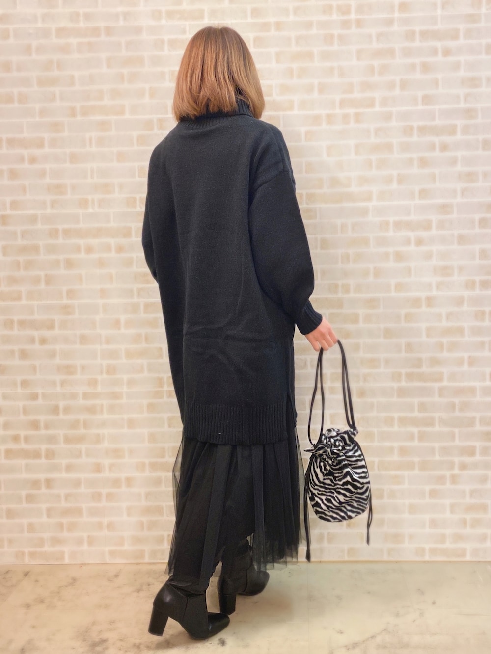 ブラック系のワンピース、ブラック系のショルダーバッグ、ブラック系のスカートを着用したレディースの冬コーディネートの2枚目の写真