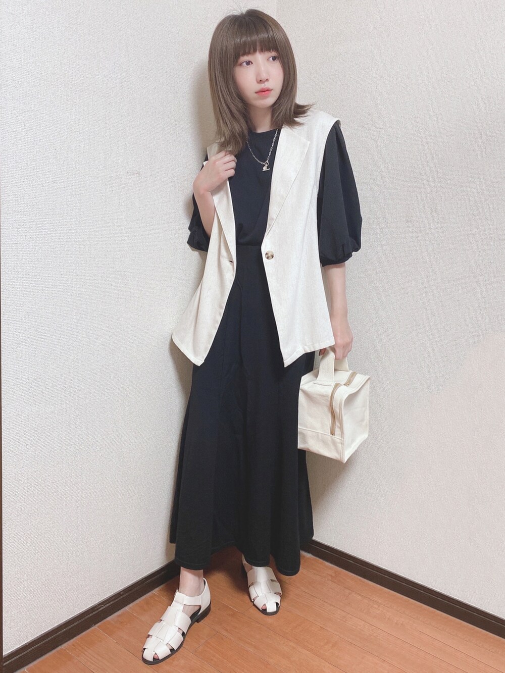 ブラック系のTシャツ/カットソー、ベージュ系のベスト、ブラック系のスカートを着用したレディースの春コーディネートの4枚目の写真