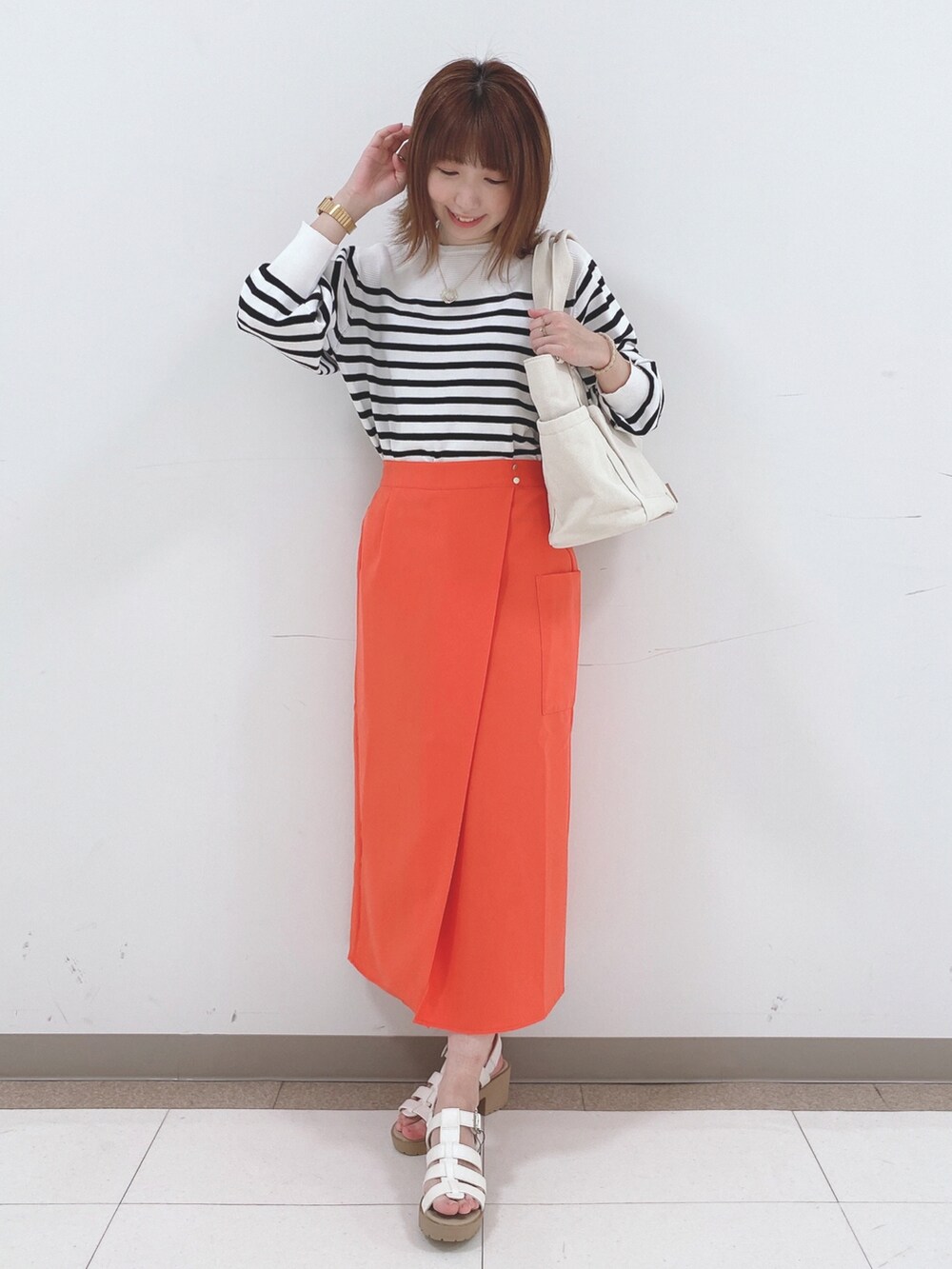 ブラック系のニット/セーター、オレンジ系のスカート、ホワイト系のサンダルを着用したレディースの春コーディネートの4枚目の写真