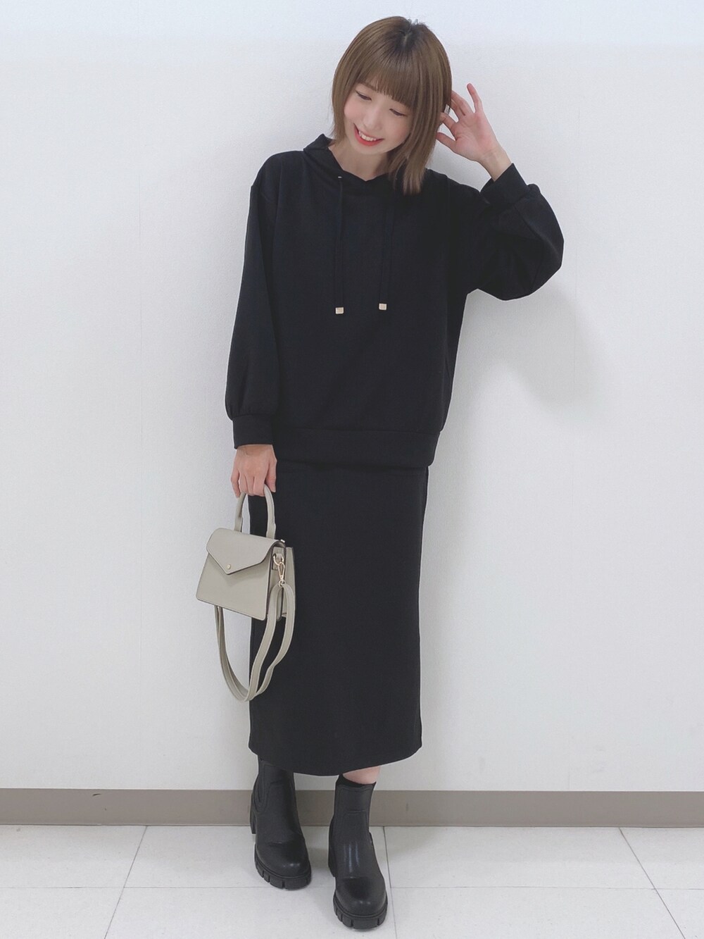 ブラック系のパーカー、ブラック系のスカート、ブラック系のブーツを着用したレディースの秋コーディネートの4枚目の写真