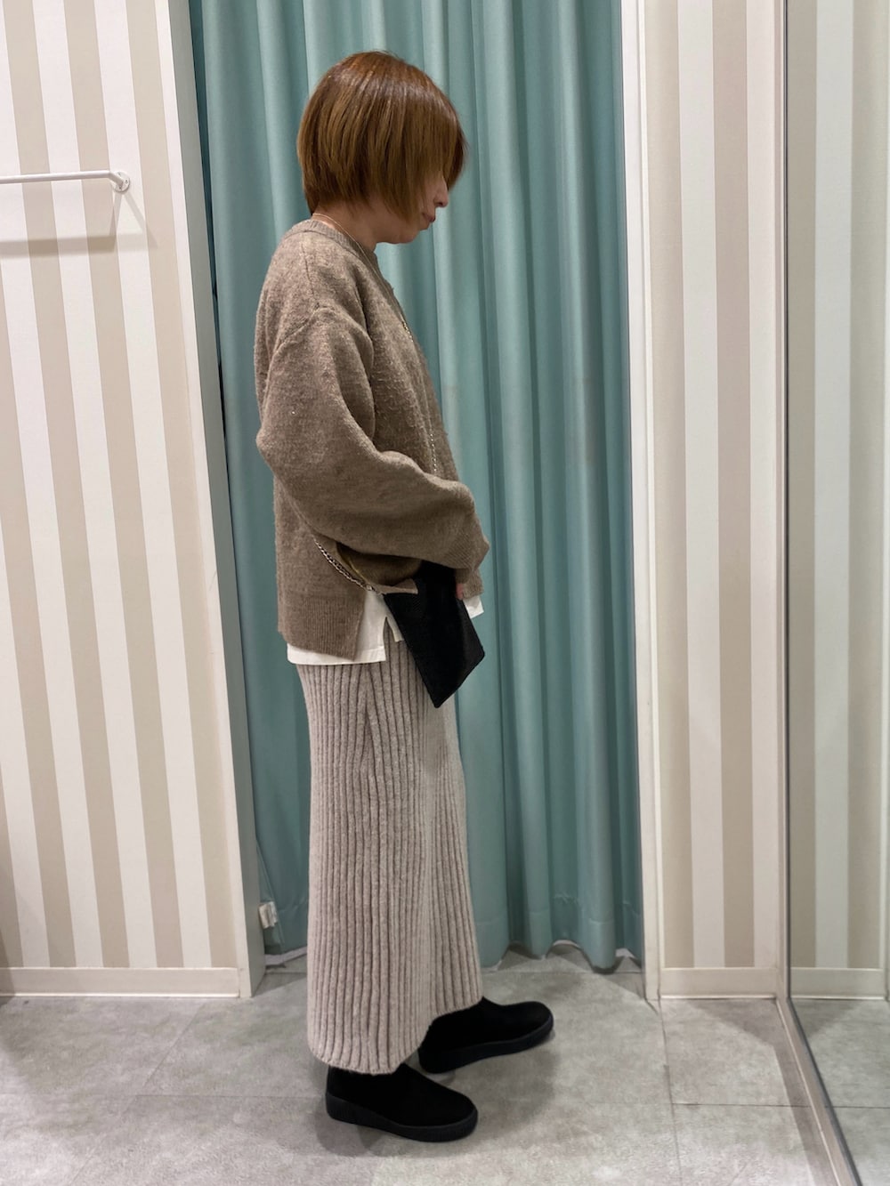 イエロー系のニット/セーター、ホワイト系のTシャツ/カットソー、ベージュ系のスカートを着用したレディースの冬コーディネートの2枚目の写真