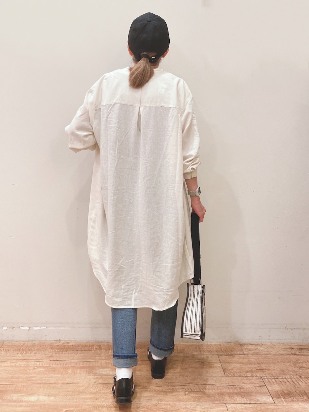 ブラウン系のタンクトップ、ホワイト系のワンピース、ブルー系のデニムパンツを着用したレディースの春コーディネートの3枚目の写真