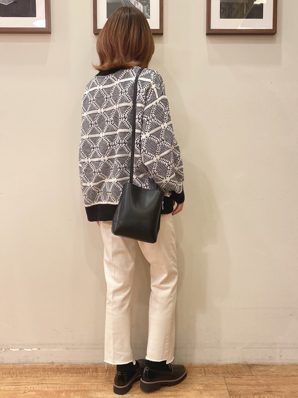 ホワイト系のニット/セーター、ブラック系のショルダーバッグ、ホワイト系のデニムパンツを着用したレディースの冬コーディネートの2枚目の写真