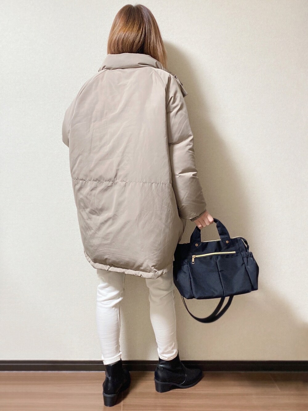 ブラック系のトートバッグ、ブラック系のニット/セーター、ブラウン系のダウンジャケット/コートを着用したレディースの冬コーディネートの2枚目の写真