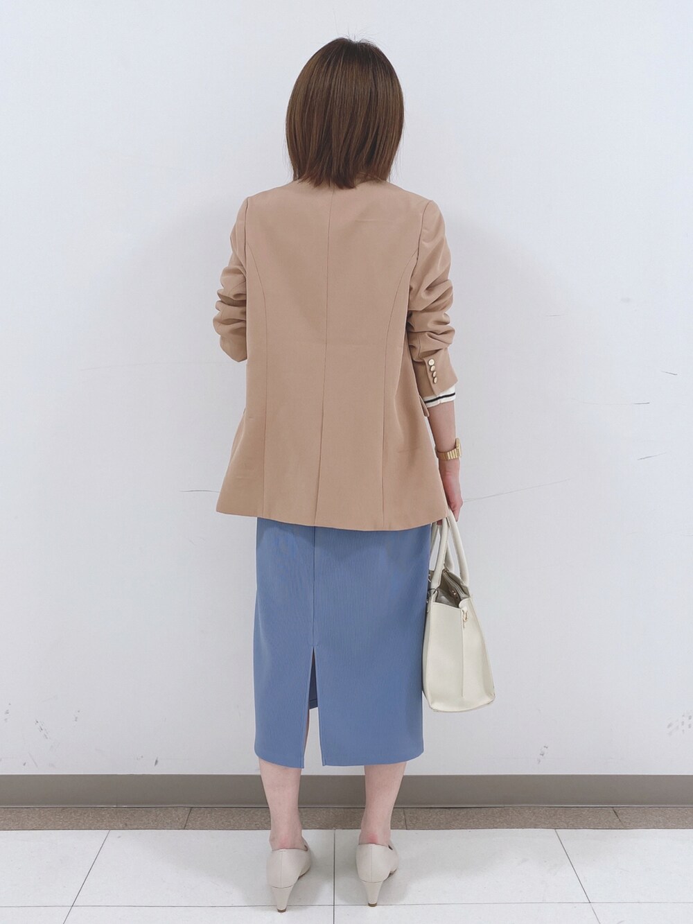 ベージュ系のテーラードジャケット、ホワイト系のニット/セーター、ブルー系のスカートを着用したレディースの冬コーディネートの3枚目の写真