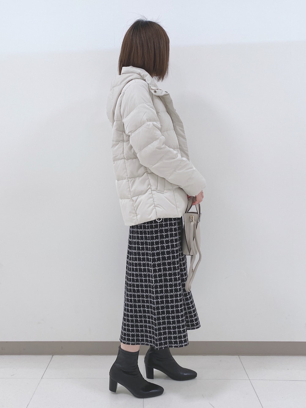 ベージュ系のダウンジャケット/コート、ブラック系のニット/セーター、ブラック系のスカートを着用したレディースの冬コーディネートの2枚目の写真