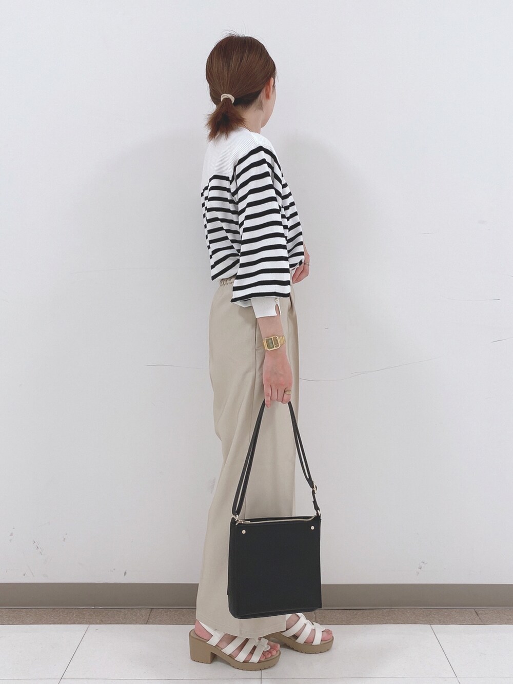 ブラック系のニット/セーター、ベージュ系のその他パンツ、ホワイト系のサンダルを着用したレディースの春コーディネートの2枚目の写真