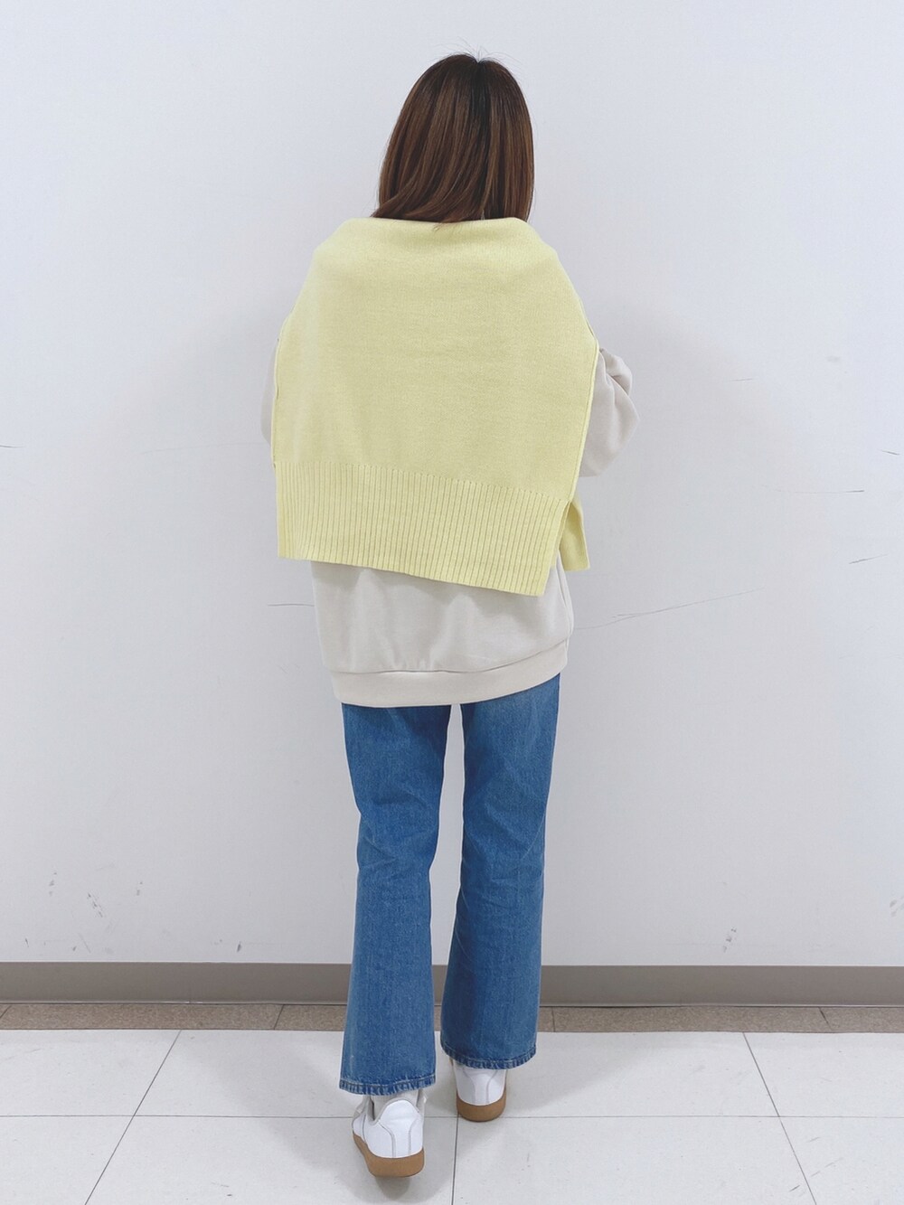 ベージュ系のスウェット、イエロー系のニット/セーター、ブルー系のデニムパンツを着用したレディースの冬コーディネートの3枚目の写真