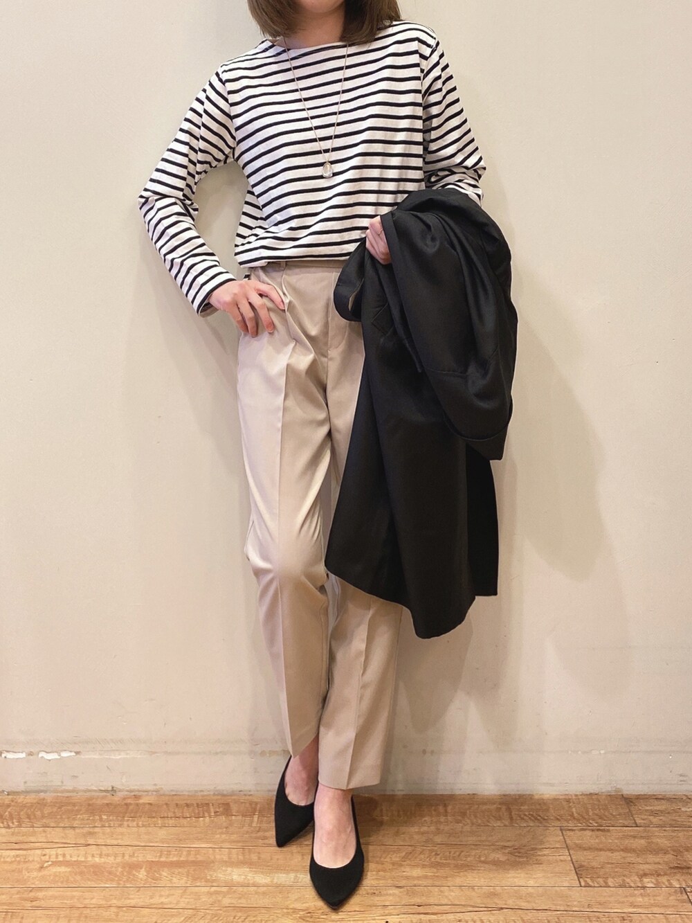 ブラック系のTシャツ/カットソー、ブラック系のトレンチコート、ベージュ系のパンツを着用したレディースの春コーディネートの4枚目の写真