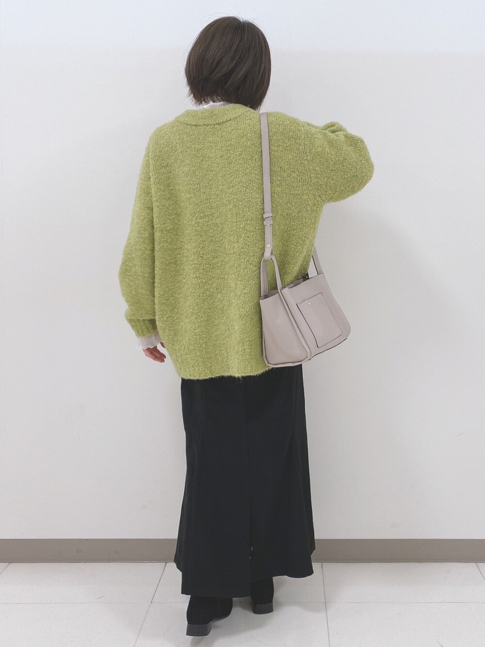 グリーン系のカーディガン/ボレロ、ホワイト系のTシャツ/カットソー、ブラック系のスカートを着用したレディースの秋コーディネートの3枚目の写真