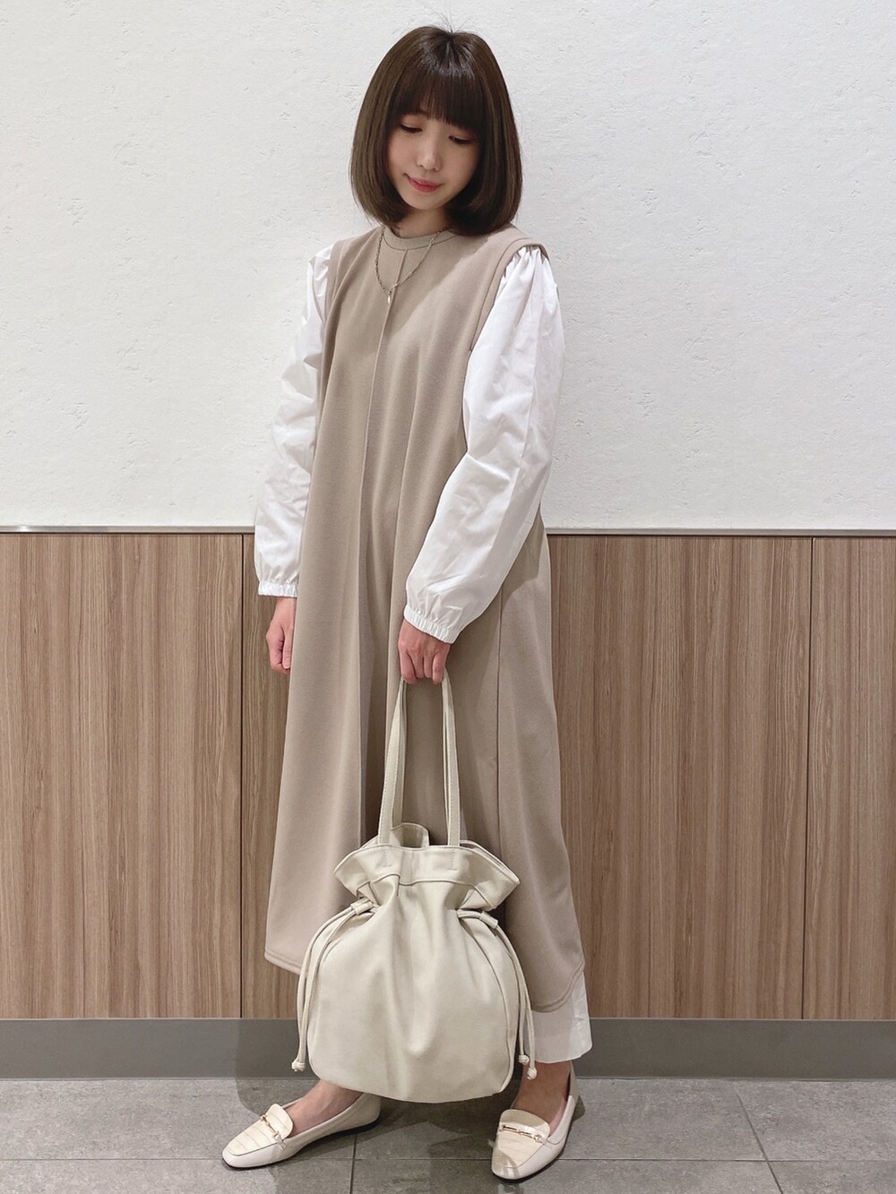 ベージュ系のワンピース、ホワイト系のドレスシューズ、ベージュ系のトートバッグを着用したレディースの春コーディネートの2枚目の写真