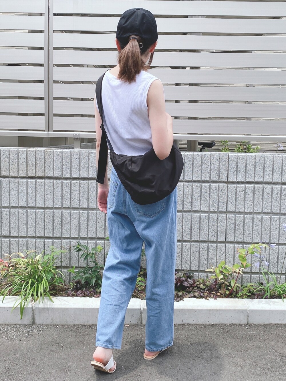 ホワイト系のタンクトップ、ブルー系のデニムパンツ、ベージュ系のサンダルを着用したレディースの夏コーディネートの2枚目の写真