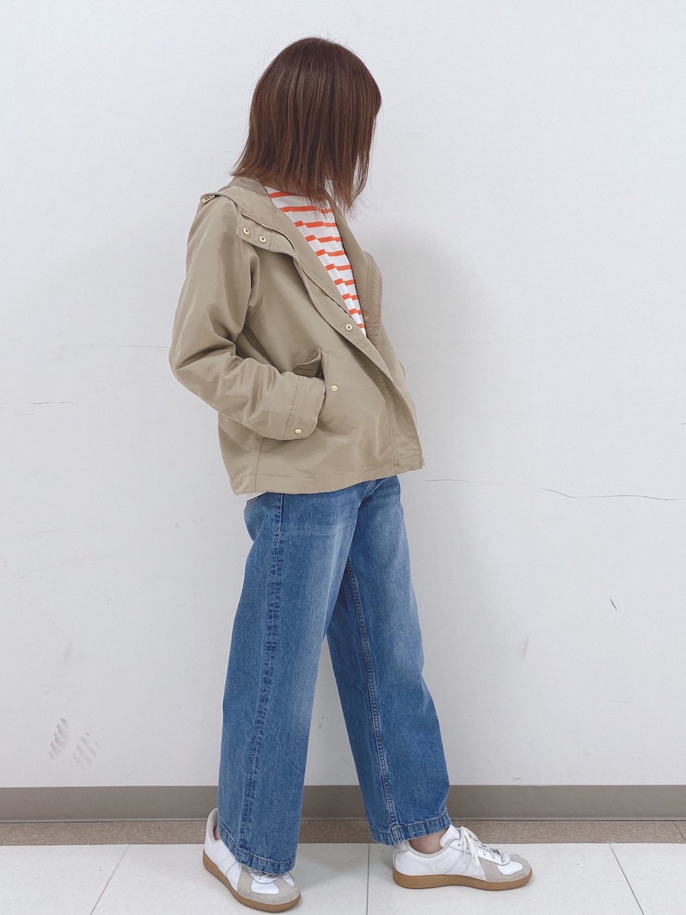 オレンジ系のTシャツ/カットソー、ベージュ系のブルゾン、ブルー系のデニムパンツを着用したレディースの春コーディネートの2枚目の写真