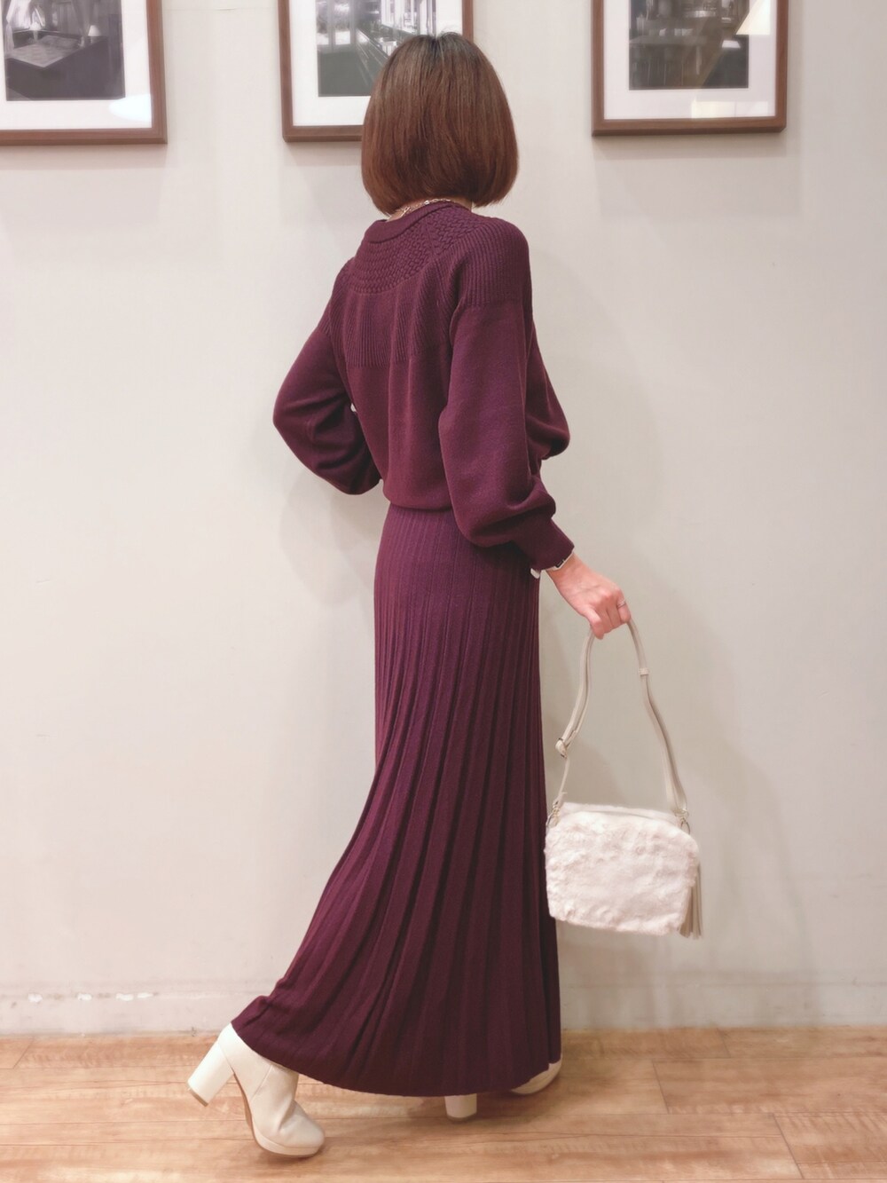 パープル系のニット/セーター、パープル系のスカート、ホワイト系のショルダーバッグを着用したレディースの秋コーディネートの2枚目の写真
