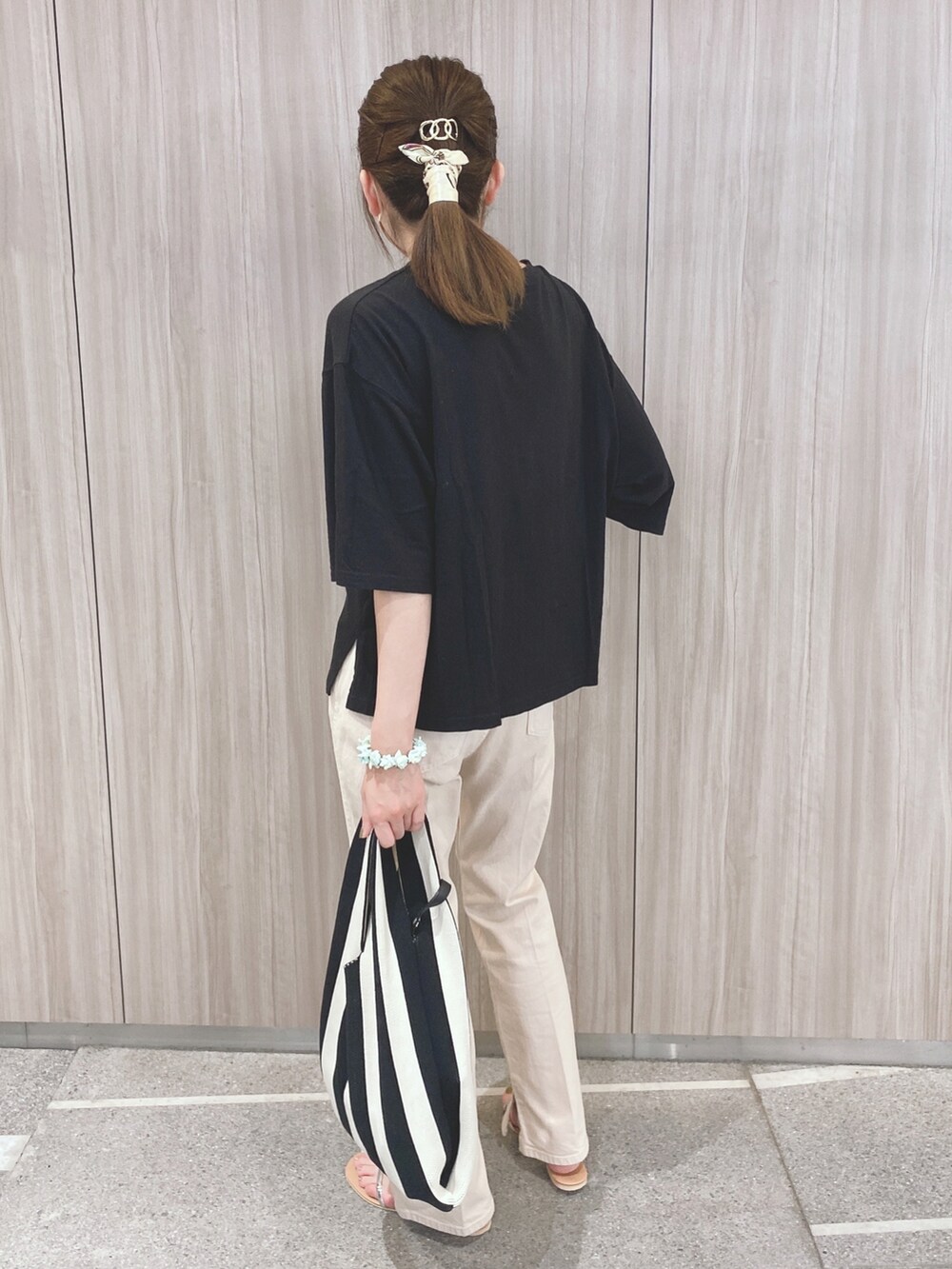 ブラック系のTシャツ/カットソー、ベージュ系のデニムパンツ、ベージュ系のサンダルを着用したレディースの夏コーディネートの2枚目の写真