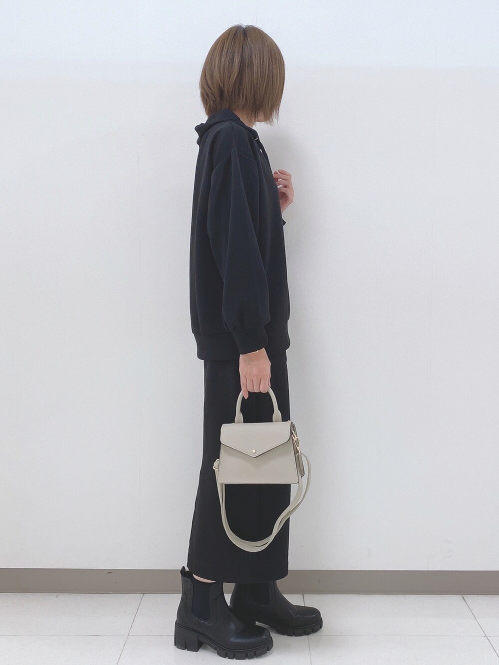 ブラック系のパーカー、ブラック系のスカート、ブラック系のブーツを着用したレディースの秋コーディネートの2枚目の写真