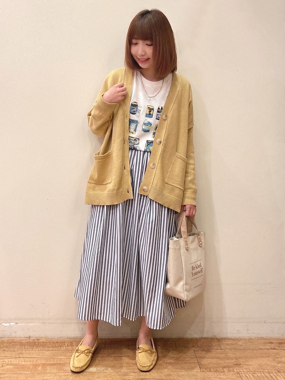 ホワイト系のTシャツ/カットソー、イエロー系のカーディガン/ボレロ、ブルー系のスカートを着用したレディースの冬コーディネートの2枚目の写真