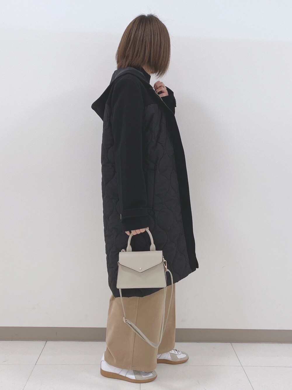 ブラック系のニット/セーター、ブラック系のその他アウター、ベージュ系のその他パンツを着用したレディースの冬コーディネートの2枚目の写真