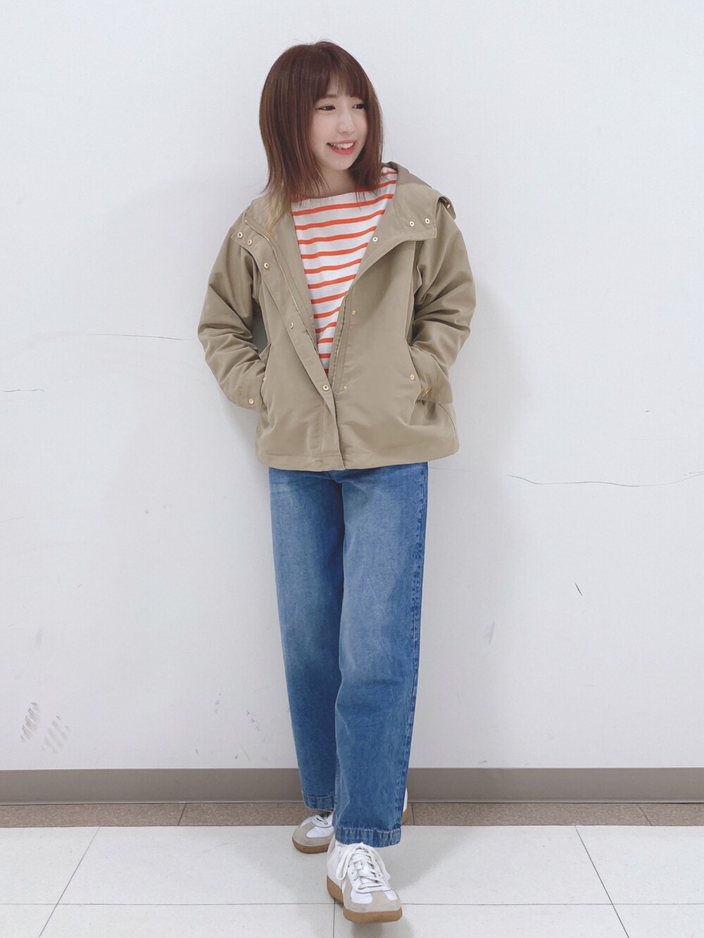 オレンジ系のTシャツ/カットソー、ベージュ系のブルゾン、ブルー系のデニムパンツを着用したレディースの春コーディネートの4枚目の写真