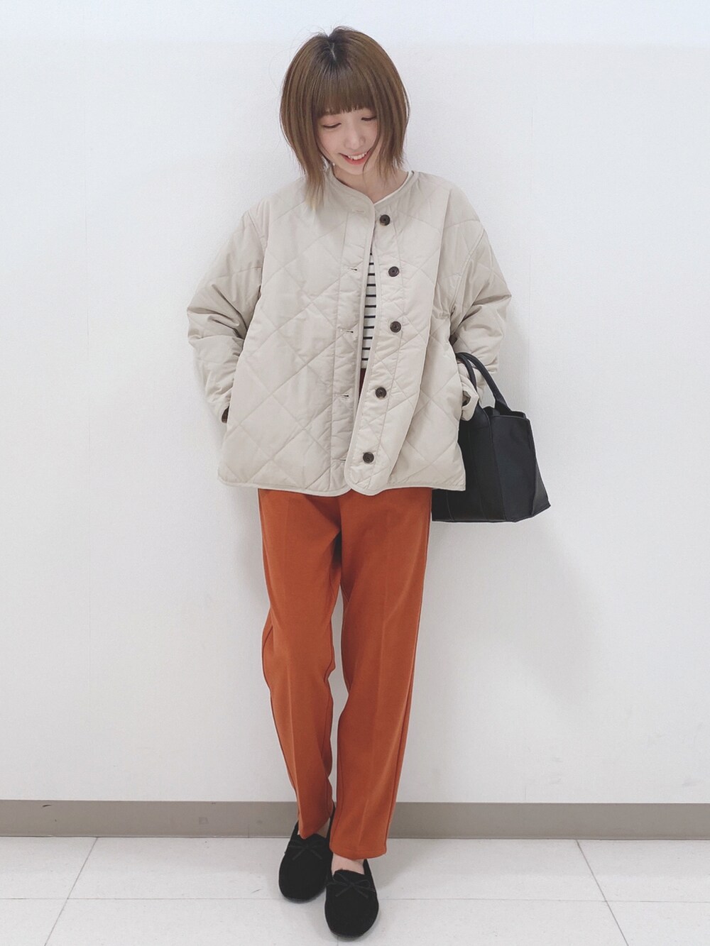 グレー系のブルゾン、ホワイト系のニット/セーター、オレンジ系のその他パンツを着用したレディースの秋コーディネートの4枚目の写真