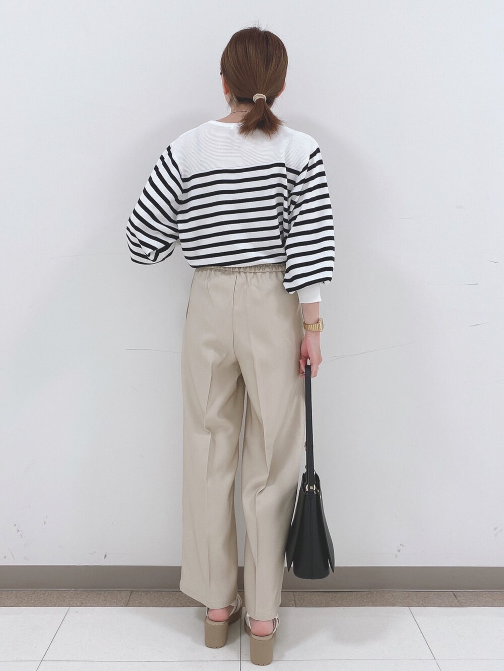 ブラック系のニット/セーター、ベージュ系のその他パンツ、ホワイト系のサンダルを着用したレディースの春コーディネートの3枚目の写真