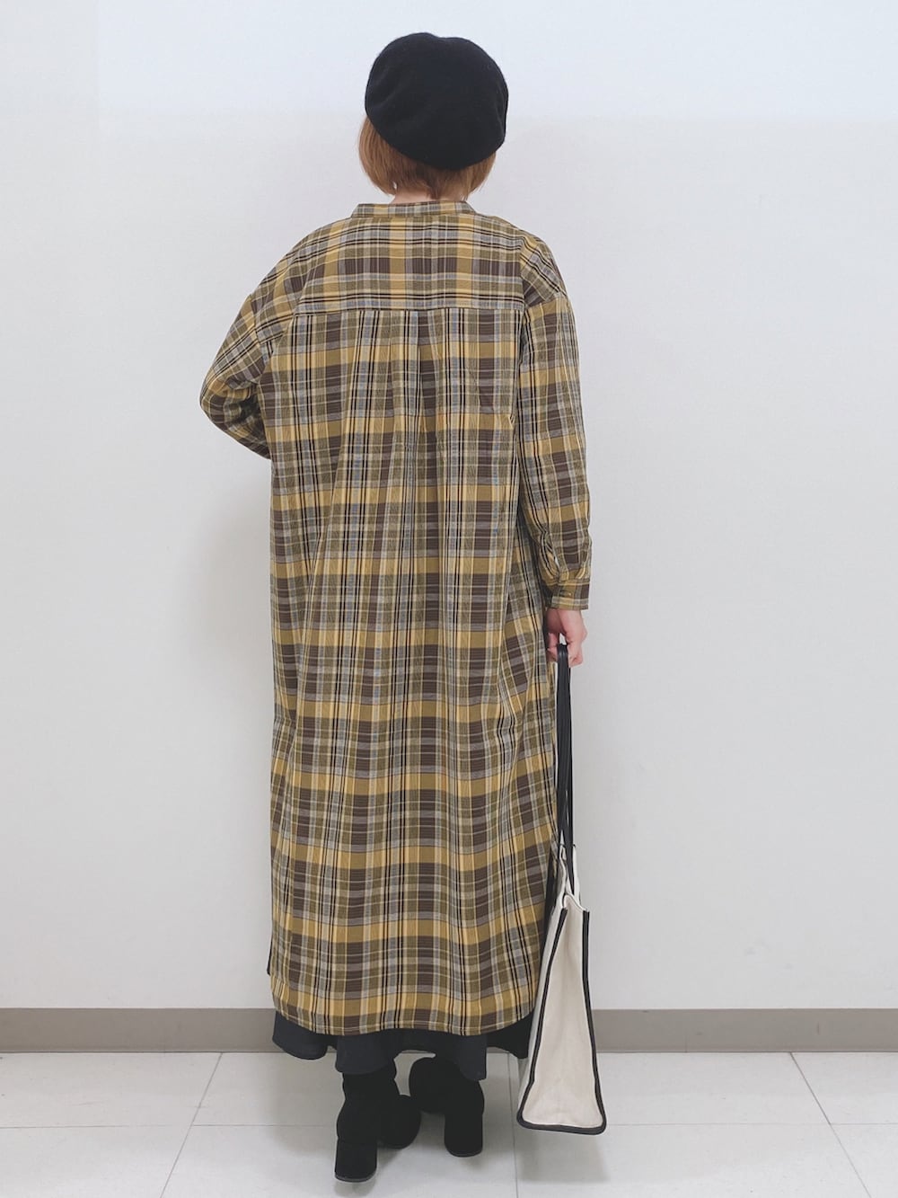 ホワイト系のTシャツ/カットソー、ブラック系のスカート、イエロー系のワンピースを着用したレディースの秋コーディネートの3枚目の写真