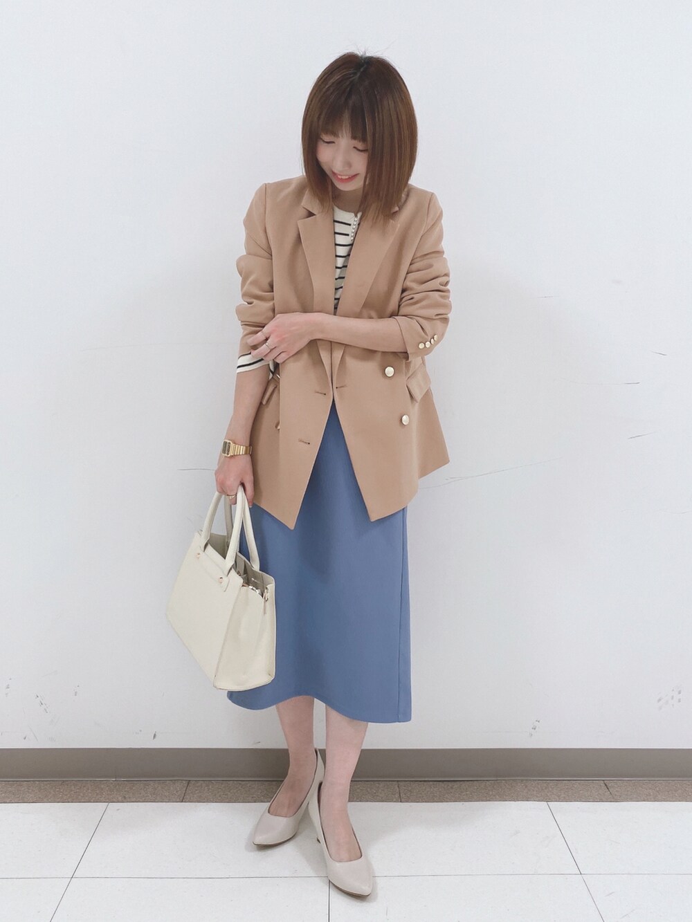 ベージュ系のテーラードジャケット、ホワイト系のニット/セーター、ブルー系のスカートを着用したレディースの冬コーディネートの4枚目の写真