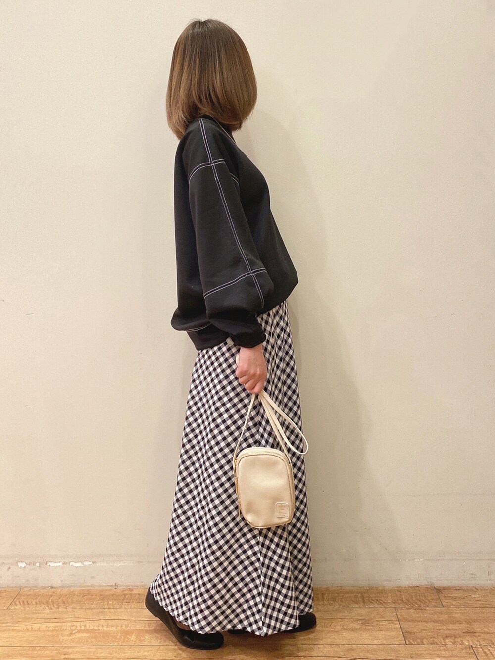 ベージュ系のショルダーバッグ、ブラック系のスカート、ブラック系のTシャツ/カットソーを着用したレディースの春コーディネートの2枚目の写真