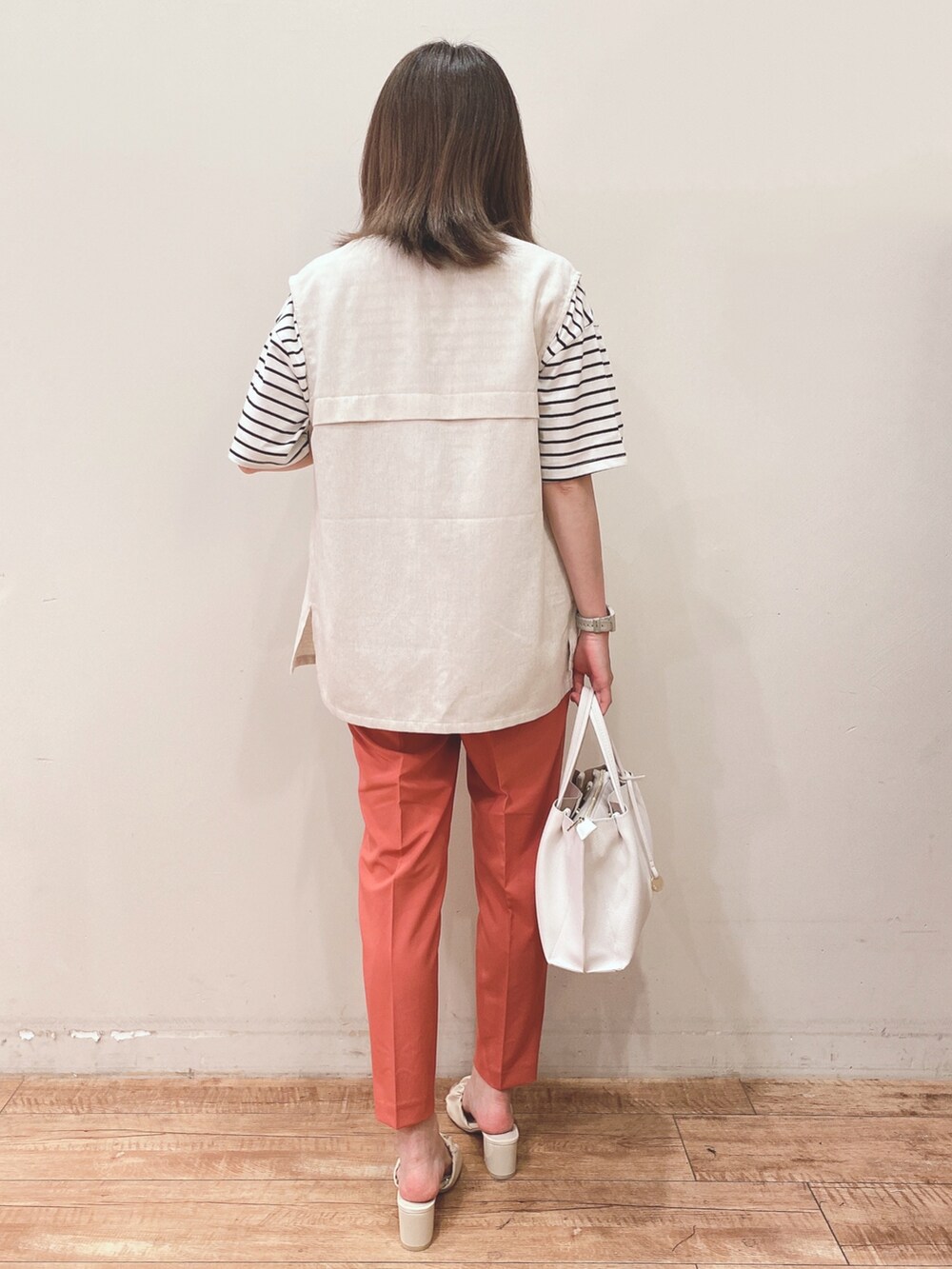 ブラック系のTシャツ/カットソー、ベージュ系のベスト、ホワイト系のショルダーバッグを着用したレディースの春コーディネートの3枚目の写真