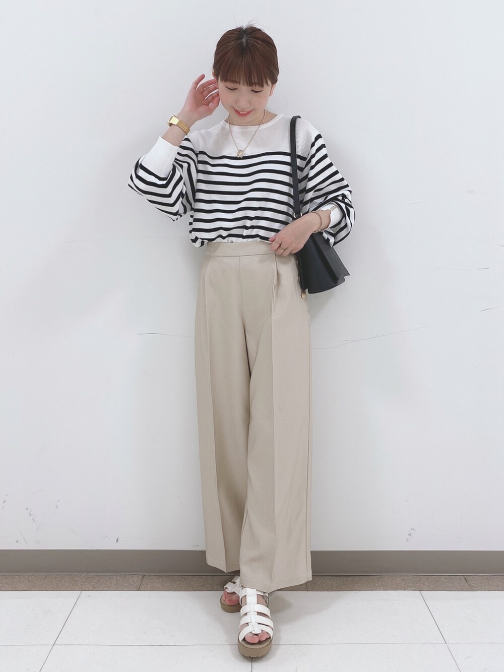 ブラック系のニット/セーター、ベージュ系のその他パンツ、ホワイト系のサンダルを着用したレディースの春コーディネートの4枚目の写真