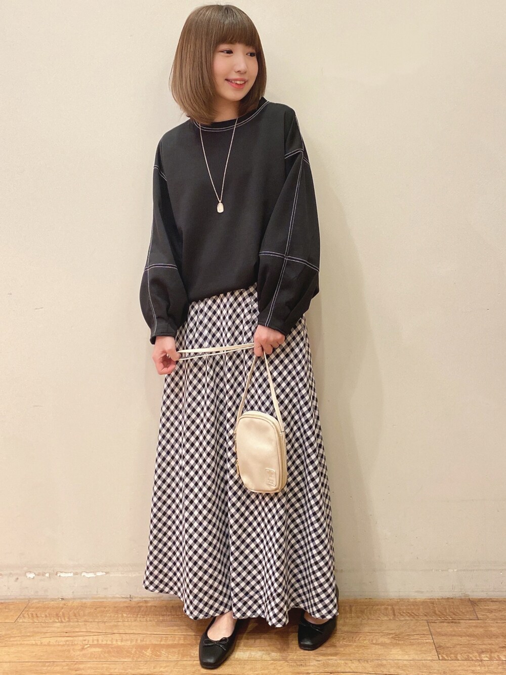 ベージュ系のショルダーバッグ、ブラック系のスカート、ブラック系のTシャツ/カットソーを着用したレディースの春コーディネートの4枚目の写真