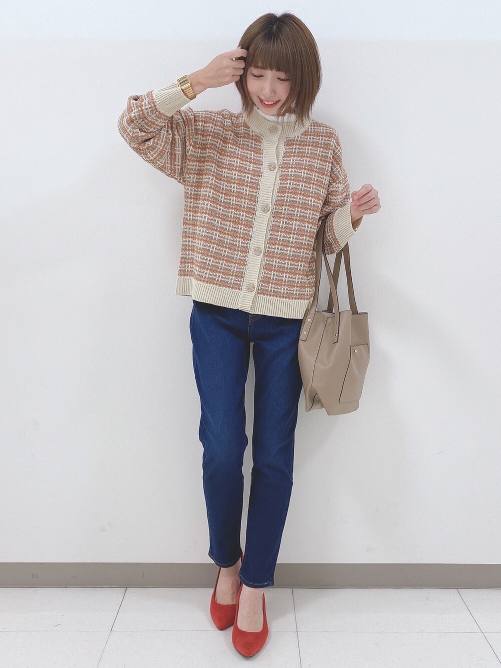 オレンジ系のカーディガン/ボレロ、ホワイト系のTシャツ/カットソー、ブルー系のデニムパンツを着用したレディースの秋コーディネートの4枚目の写真