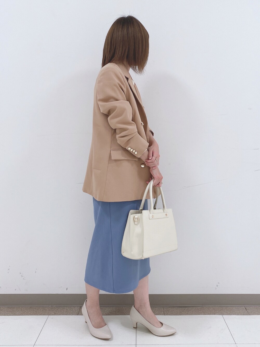 ベージュ系のテーラードジャケット、ホワイト系のニット/セーター、ブルー系のスカートを着用したレディースの冬コーディネートの2枚目の写真