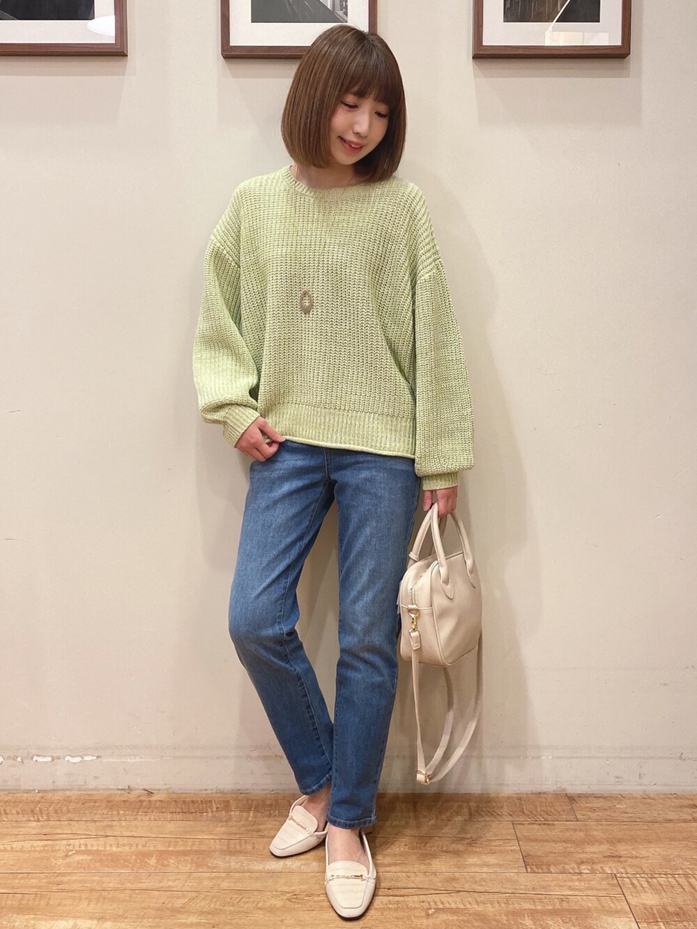 グリーン系のニット/セーター、ブルー系のデニムパンツ、ホワイト系のショルダーバッグを着用したレディースの冬コーディネートの2枚目の写真