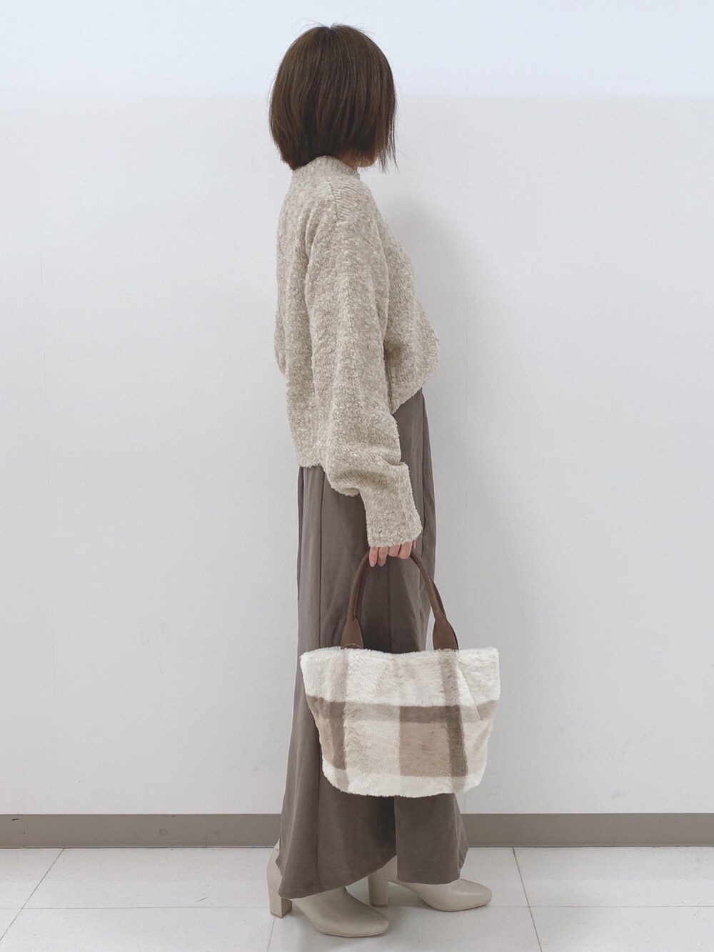 ベージュ系のニット/セーター、ブラウン系のスカート、ホワイト系のブーツを着用したレディースの秋コーディネートの2枚目の写真