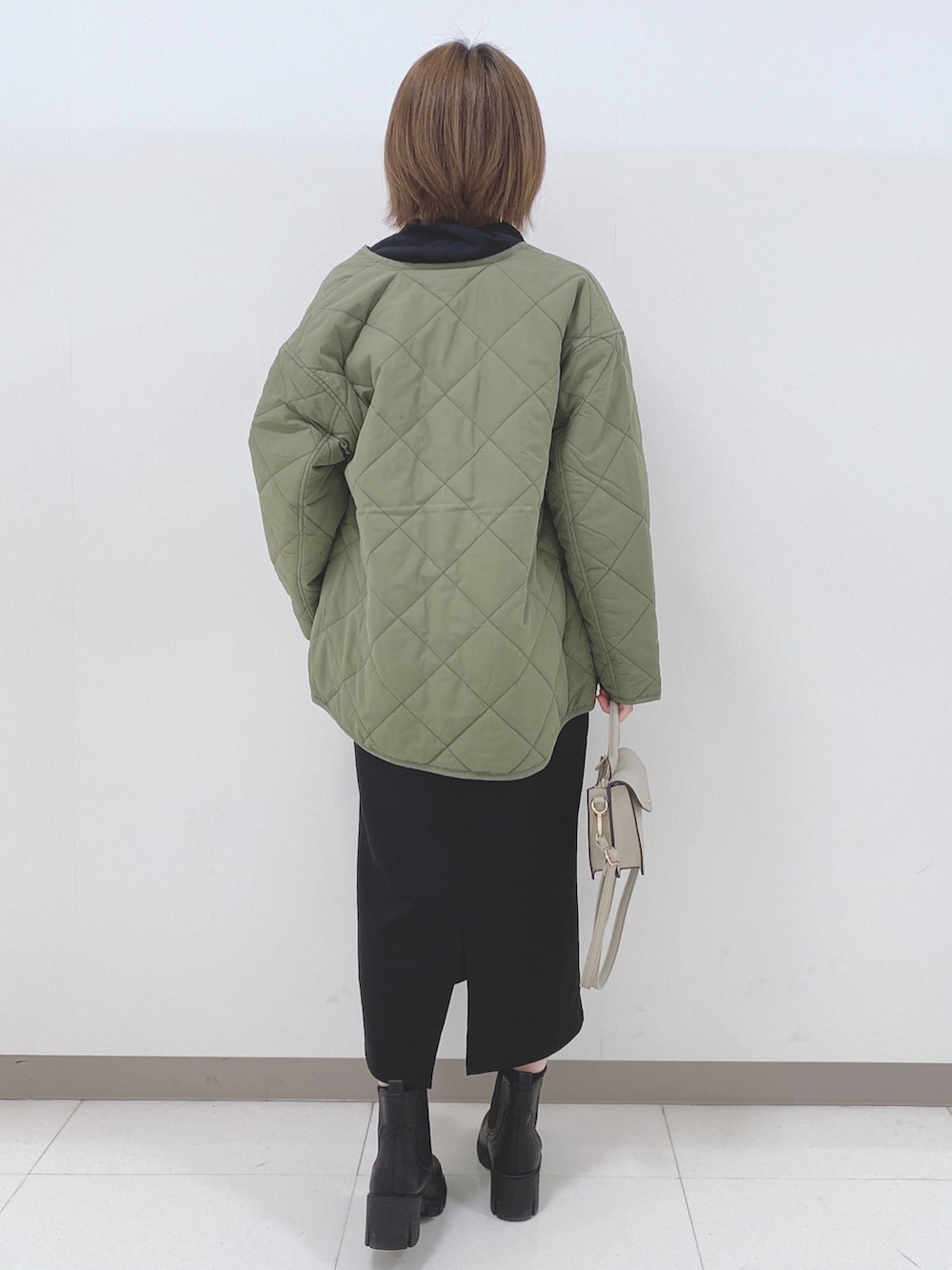 ブラック系のパーカー、グリーン系のブルゾン、ブラック系のスカートを着用したレディースの秋コーディネートの3枚目の写真