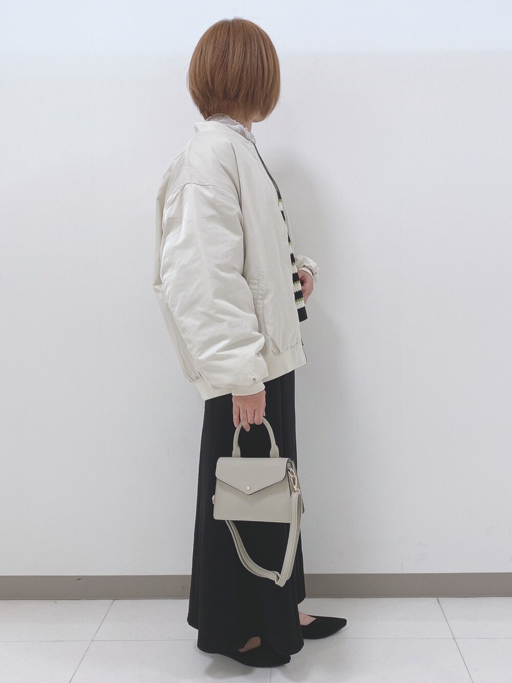 ベージュ系のブルゾン、ブラック系のニット/セーター、ホワイト系のTシャツ/カットソーを着用したレディースの秋コーディネートの2枚目の写真