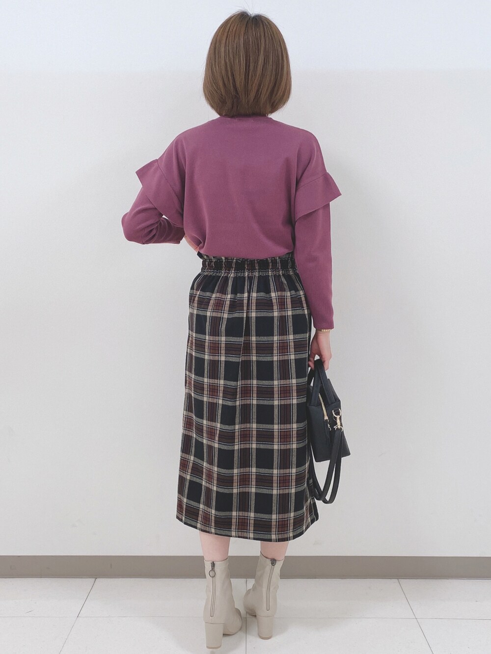 ピンク系のニット/セーター、ブラック系のスカート、ホワイト系のブーツを着用したレディースの秋コーディネートの3枚目の写真