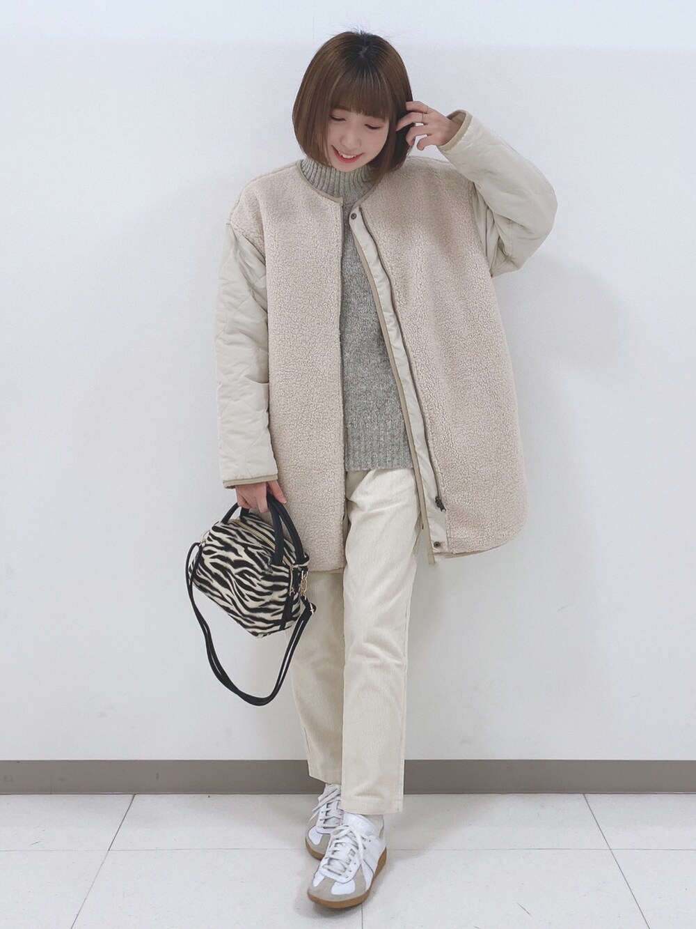 ベージュ系のノーカラージャケット、ベージュ系のニット/セーター、ホワイト系のスニーカーを着用したレディースの秋コーディネートの4枚目の写真