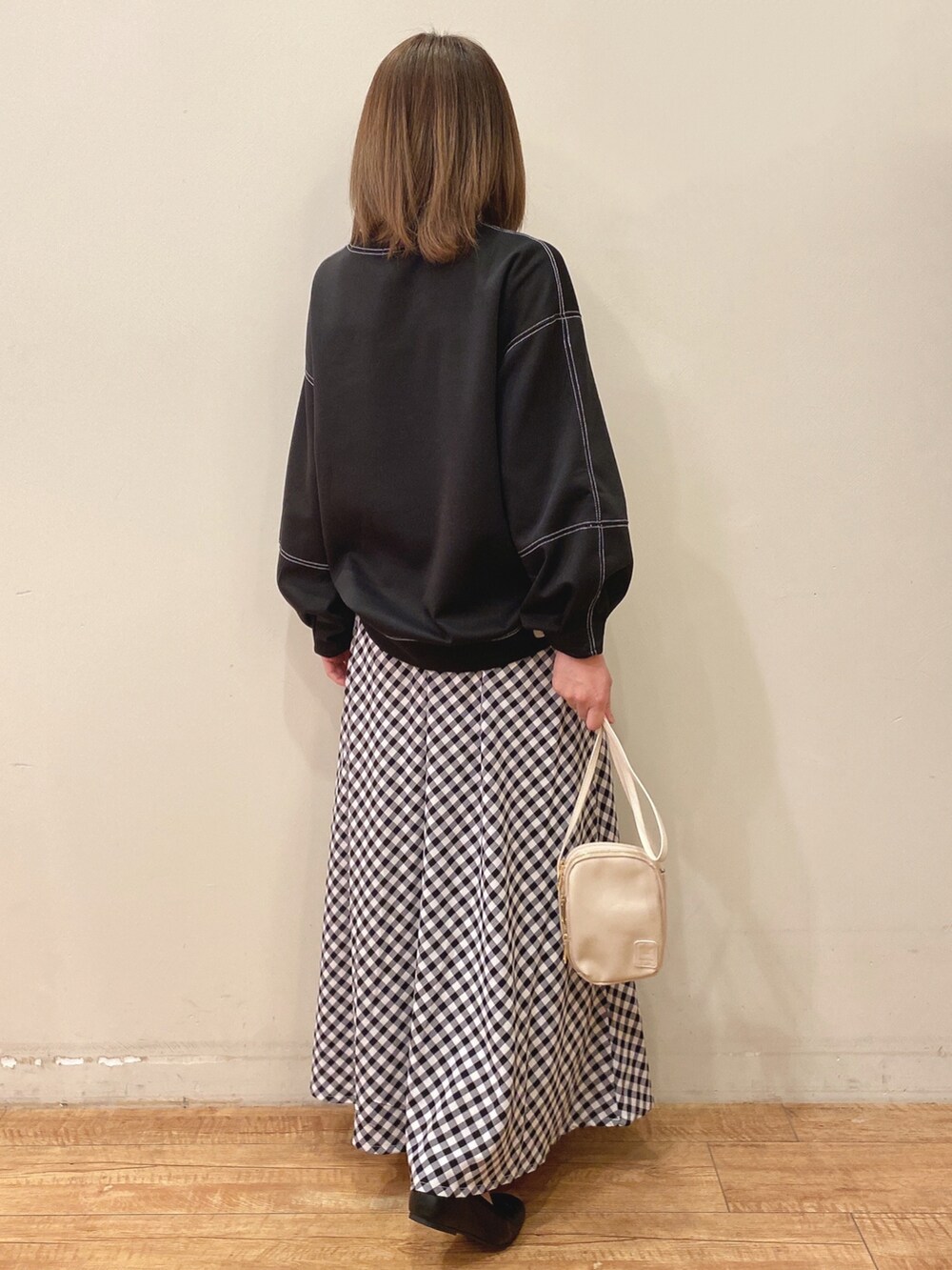 ベージュ系のショルダーバッグ、ブラック系のスカート、ブラック系のTシャツ/カットソーを着用したレディースの春コーディネートの3枚目の写真