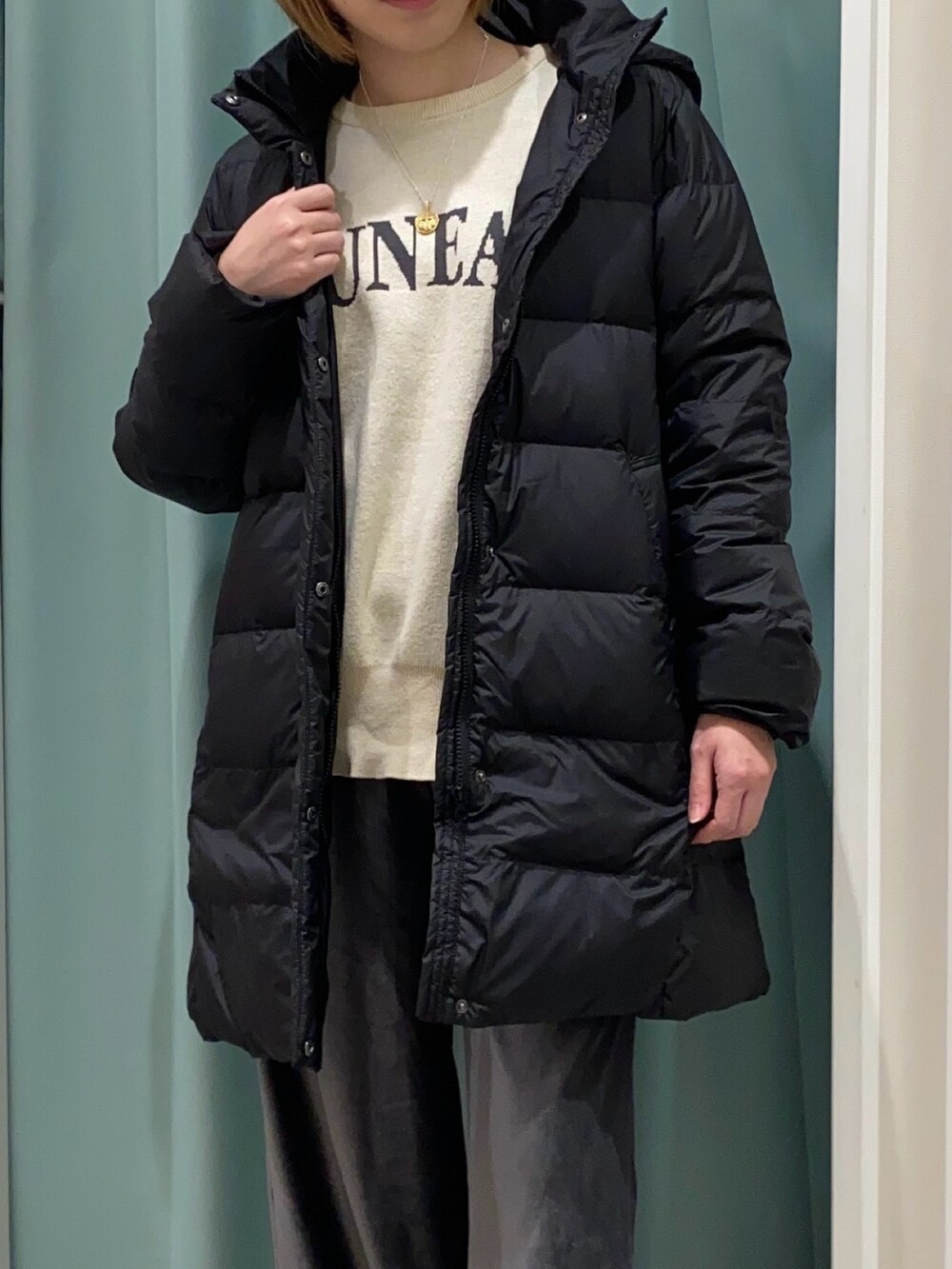 ブラック系のダウンジャケット/コート、ホワイト系のニット/セーター、グレー系のその他パンツを着用したレディースの秋コーディネートの4枚目の写真